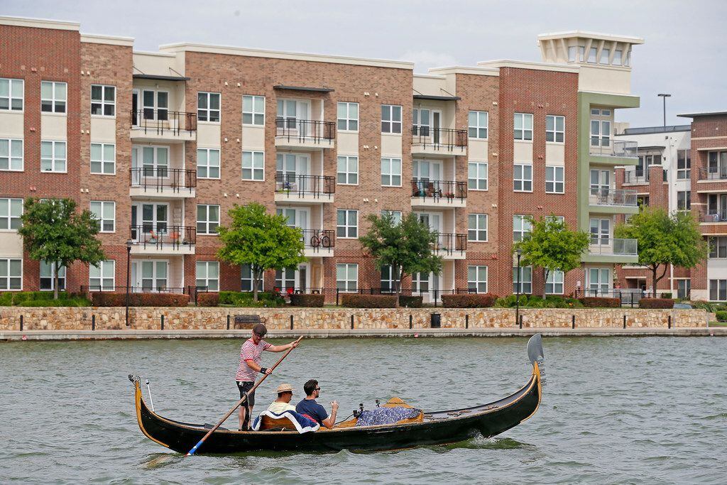 The gondola cruises past apartment complexes and construction sites on Lake Carolyn in Irving.