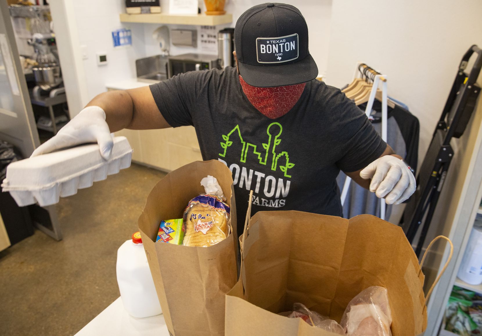 Clifton Reese, general manager at The Market at Bonton Farms, prepares bags of groceries for...