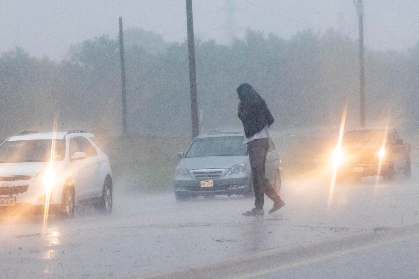 A pedestrian attempts to cross the street as rain pours down on Monday, Aug. 22, 2022, in...