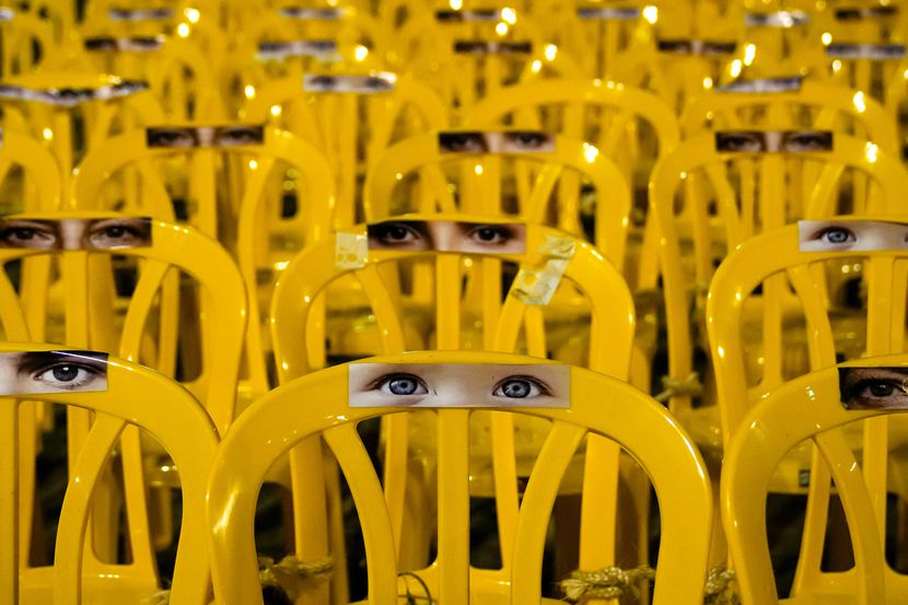 Images of human eyes are placed on empty chairs tied together in an art installation...
