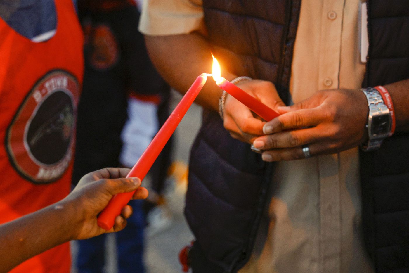 Preston Malone II (right) lights a candle before a balloon release in memory of 11-year-old...