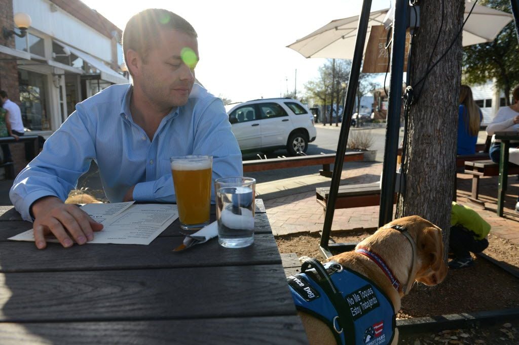 Dustin Deweerd stops to grab a drink at Oddfellows with his 3-year-old Labrador service dog...