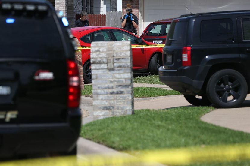 A crime scene photographer takes a photo of a vehicle in the driveway of the Ponder home...