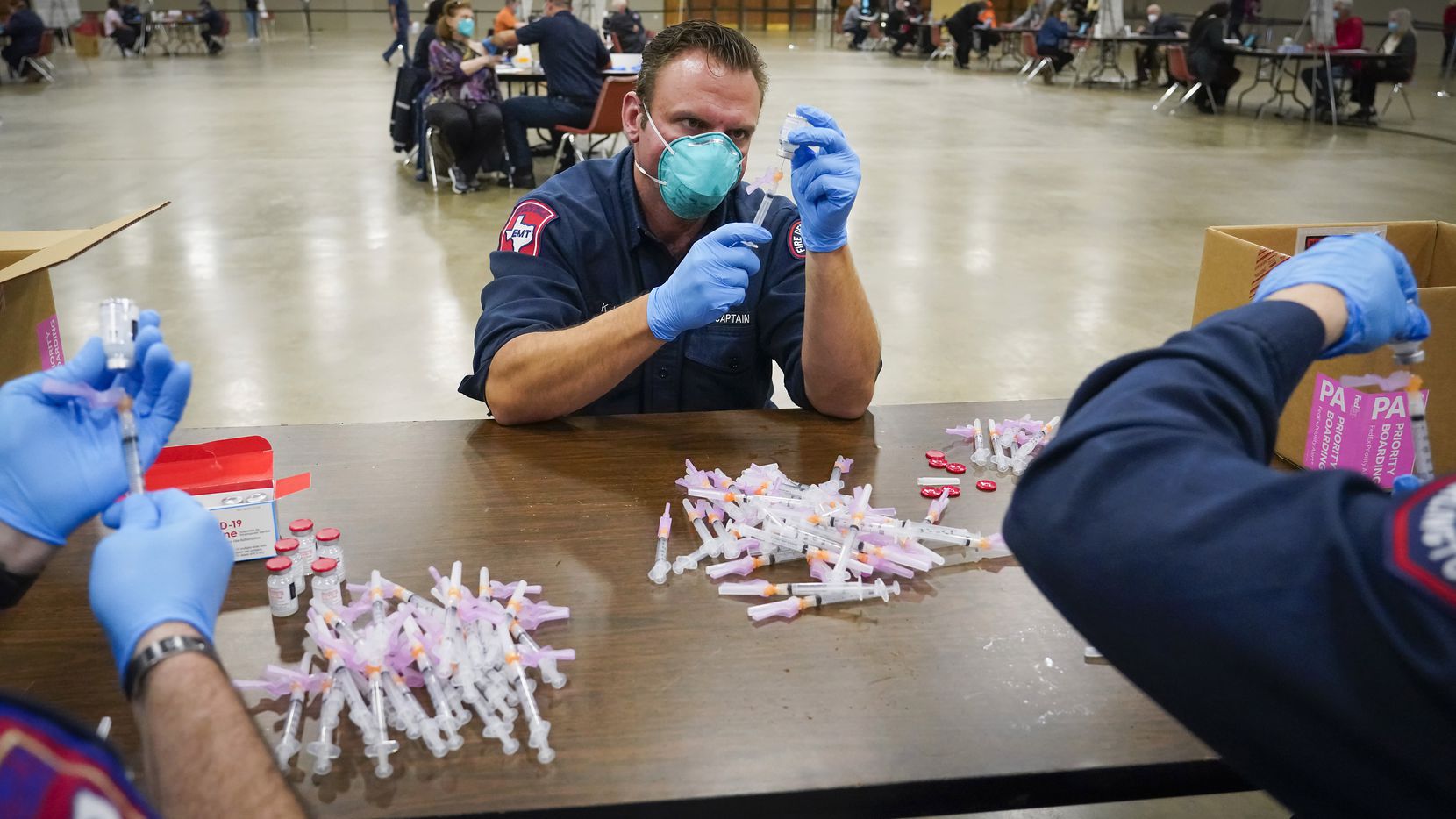Arlington Fire Department captain K.J. Land  prepares doses of the Moderna COVID-19 vaccine...
