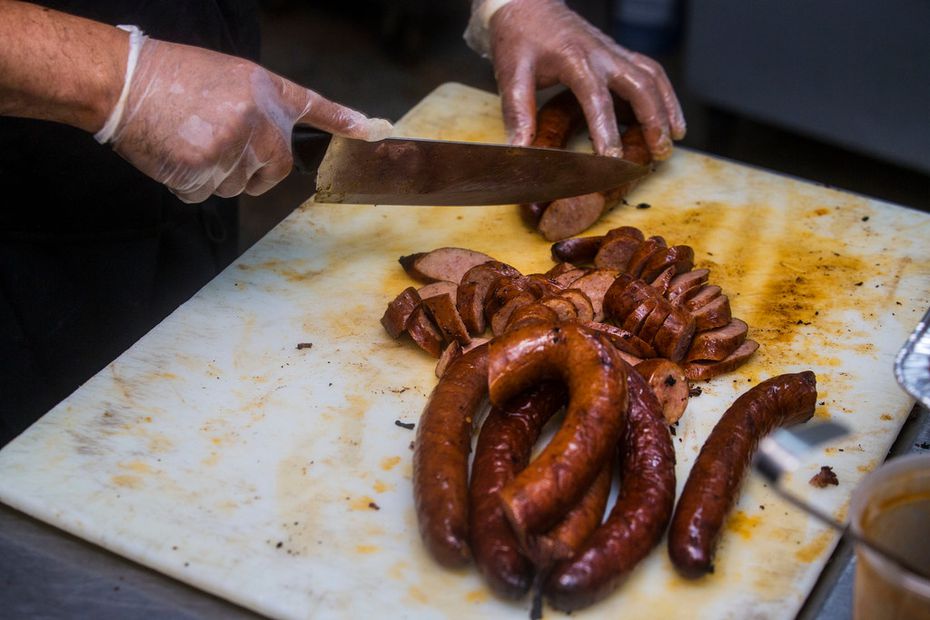 Pitmaster Jaime Salazar cuts sausage at Lakewood's First & 10 in Dallas. Smokey John's used...