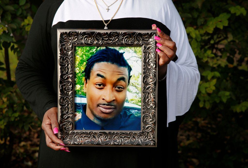 O'Shae Terry's mother, Sherley Woods, holds a portrait of her son, who was shot and killed...
