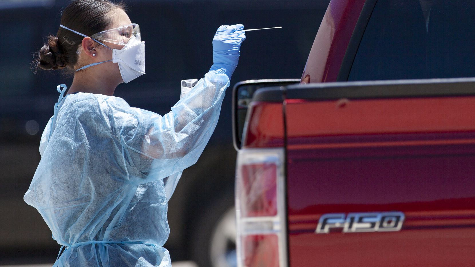 A medical worker conducts a COVID19 test on a passenger during the FEMA mobile drive-through...