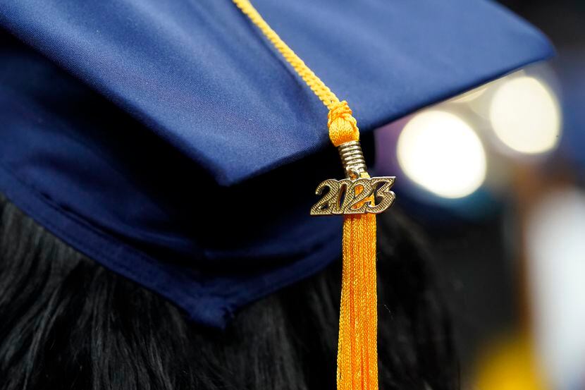 A tassel with 2023 on it rests on a graduation cap as students walk in a procession for...