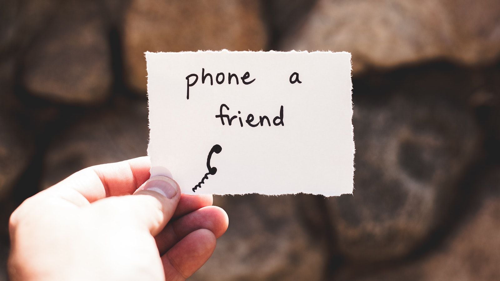 hand holding a note that reads phone a friend