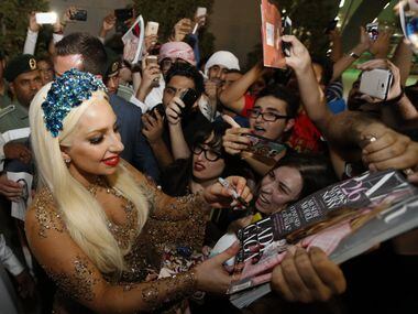 US pop star Lady Gaga signs her autograph for fans as she arrives at Dubai International...