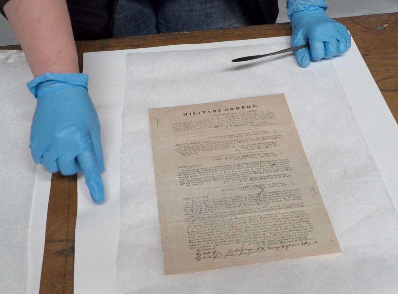 Paper conservator Lyzanne Gann examines the Juneteenth proclamation from 1865 that noted the...