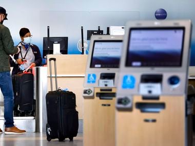 An American Airlines customer assistance representative checks-in a passenger in Terminal A at Dallas-Fort Worth International Airport, Wednesday, March 24, 2021. (Tom Fox/The Dallas Morning News) 