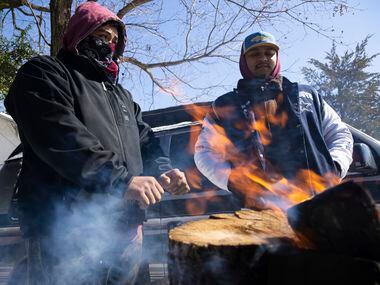 (From left) brothers Alfredo Colon and Eduardo Colon chat over a fire in front of their East...