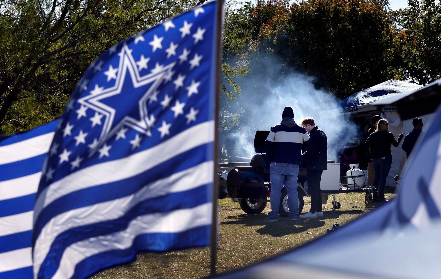 Dallas Cowboys fans cook their Thanksgiving feast on a grill during a tailgate party outside...
