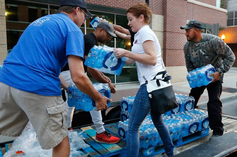 Pedro Frias (right) of Dallas helps volunteers transfer three pallets of water to a United...