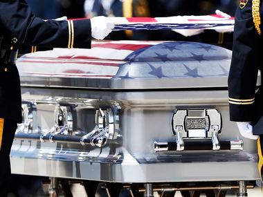 The colors of the Stars and Stripes are reflected on the surface of the coffin as the...