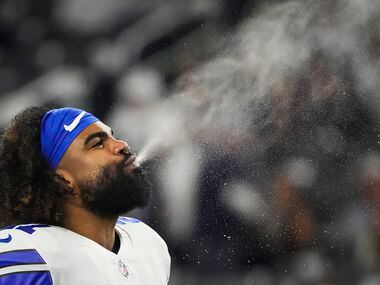 Dallas Cowboys running back Ezekiel Elliott spits water as the team warms up before an NFL...