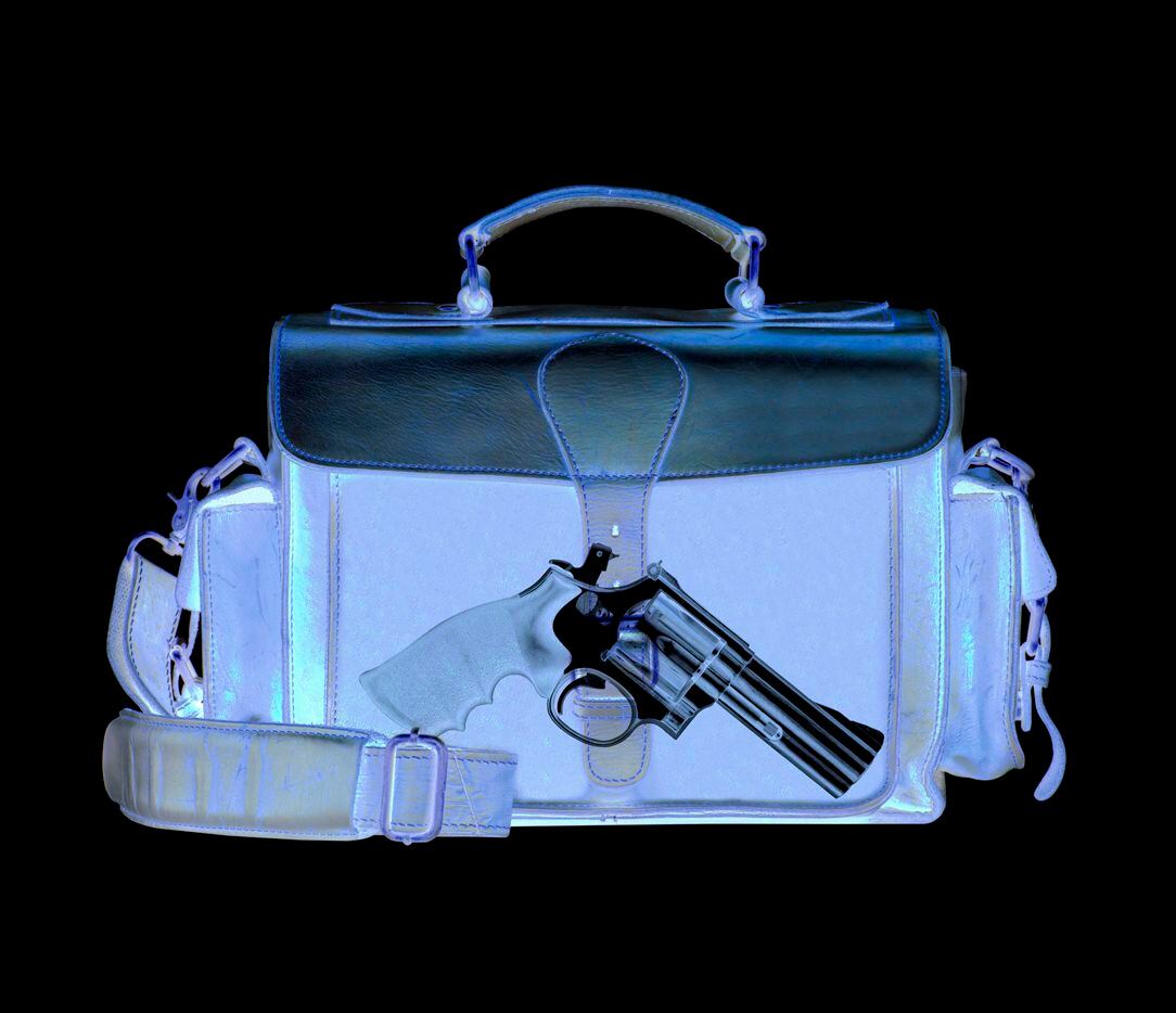 Una imagen de rayos X que muestra a una pistola en una maleta de viaje.