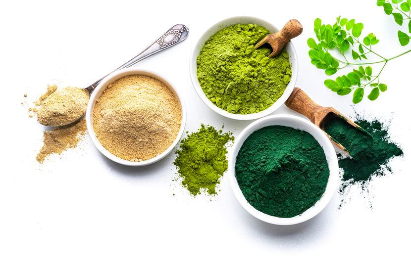 Nutritional supplements: Overhead view of Spirulina, Maca and Moringa powder in white bowls...