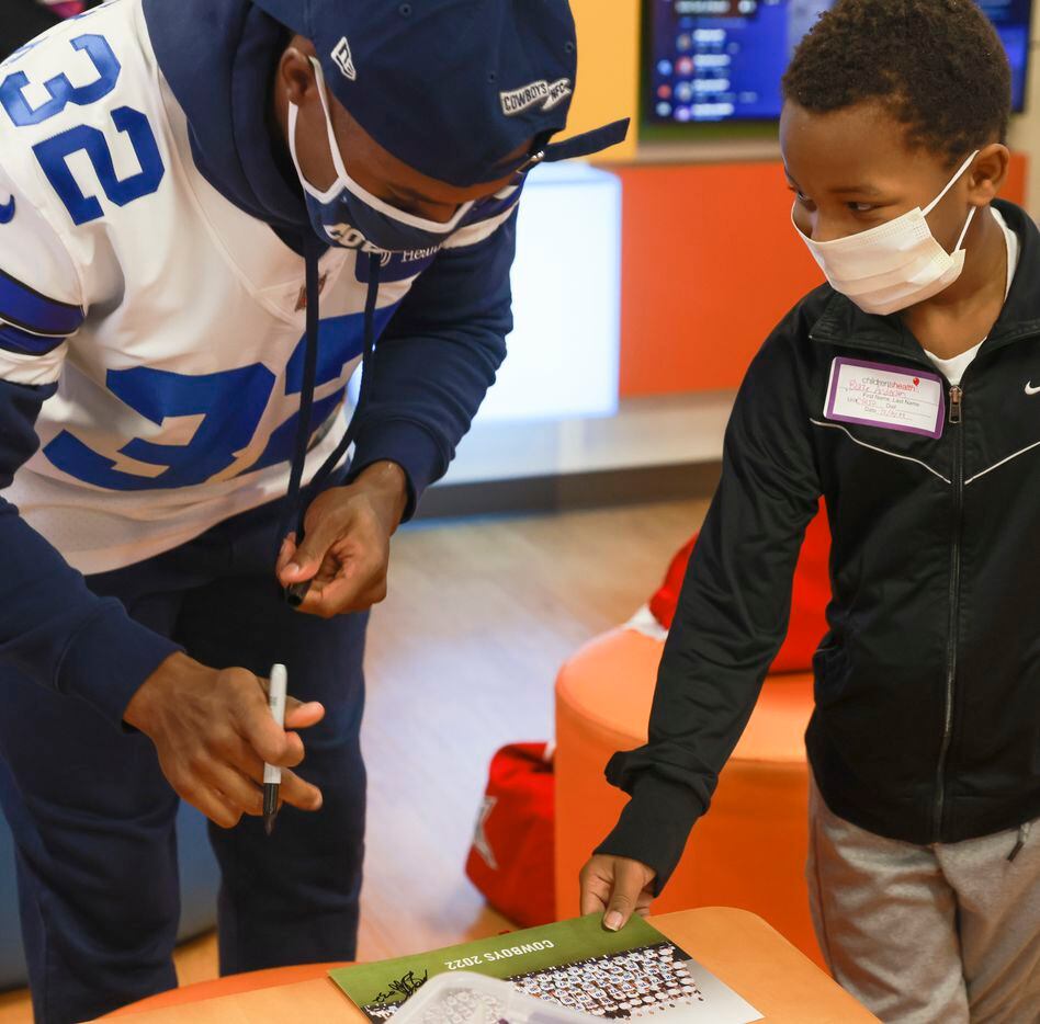 Blaze Anderson looks at Dallas Cowboys cornerback Kendall Sheffield (32) after he autographs...