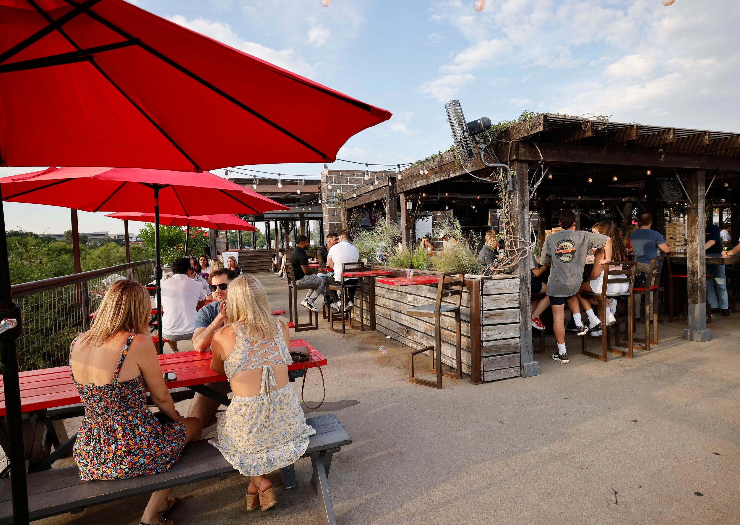 People sit on the patio at HG Sply Co. in the Lower Greenville neighborhood in Dallas,...