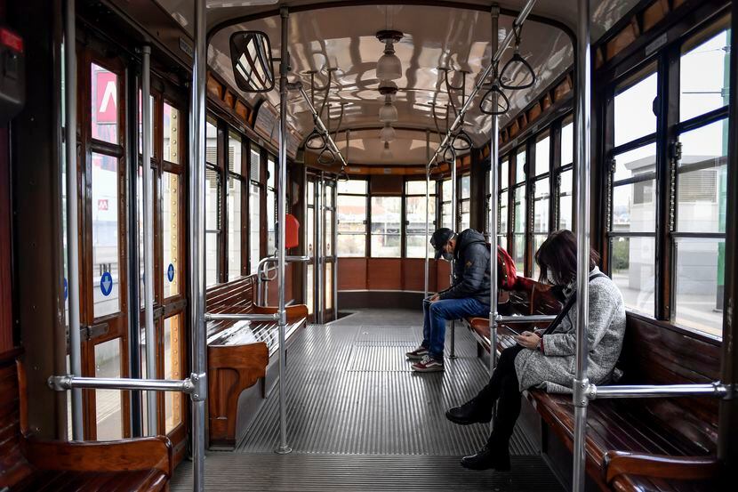 People wear sanitary masks as they ride an empty tram in downtown Milan, Italy, Wednesday,...