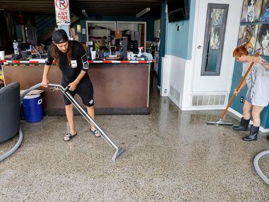 Airto Castañeda-Cudney, Ellum Electric owner (left), and Katheryn Jones clean up water after...