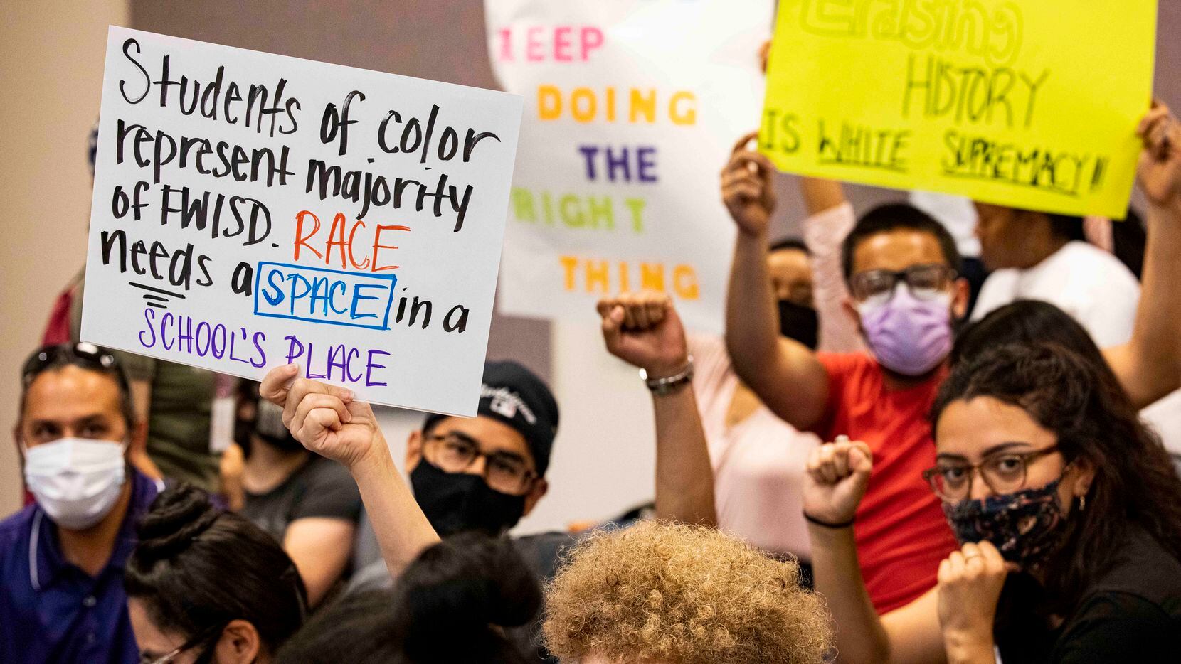Community members held signs during a Fort Worth ISD board meeting in June.