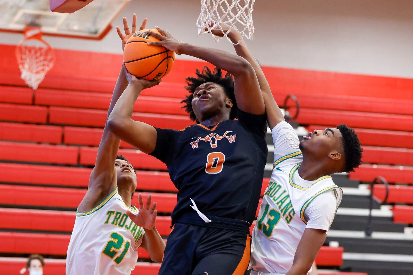 W.T. White forward Dre Cole (0) attempts a layup between Madison forwards Spencer McLeod (21) and Quintin Spencer (13) during the second quarter of a Dallas ISD Holiday Invitational basketball tournament game at Woodrow Wilson High School in Dallas, Tuesday, Dec. 28, 2021.