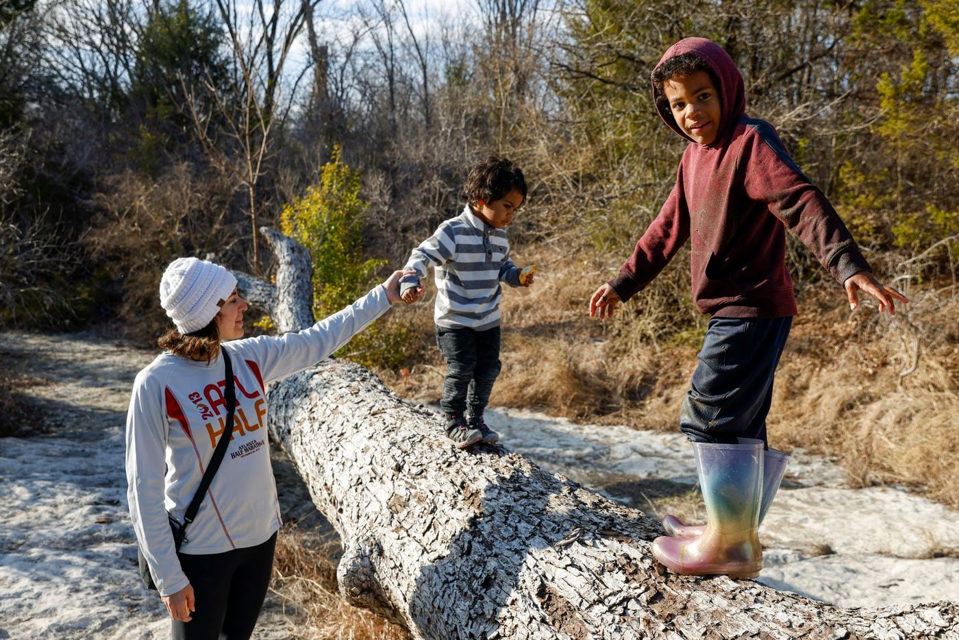 Judah Koontz, 5, walks along a fallen tree as his mother Sarah Koontz helps his younger...