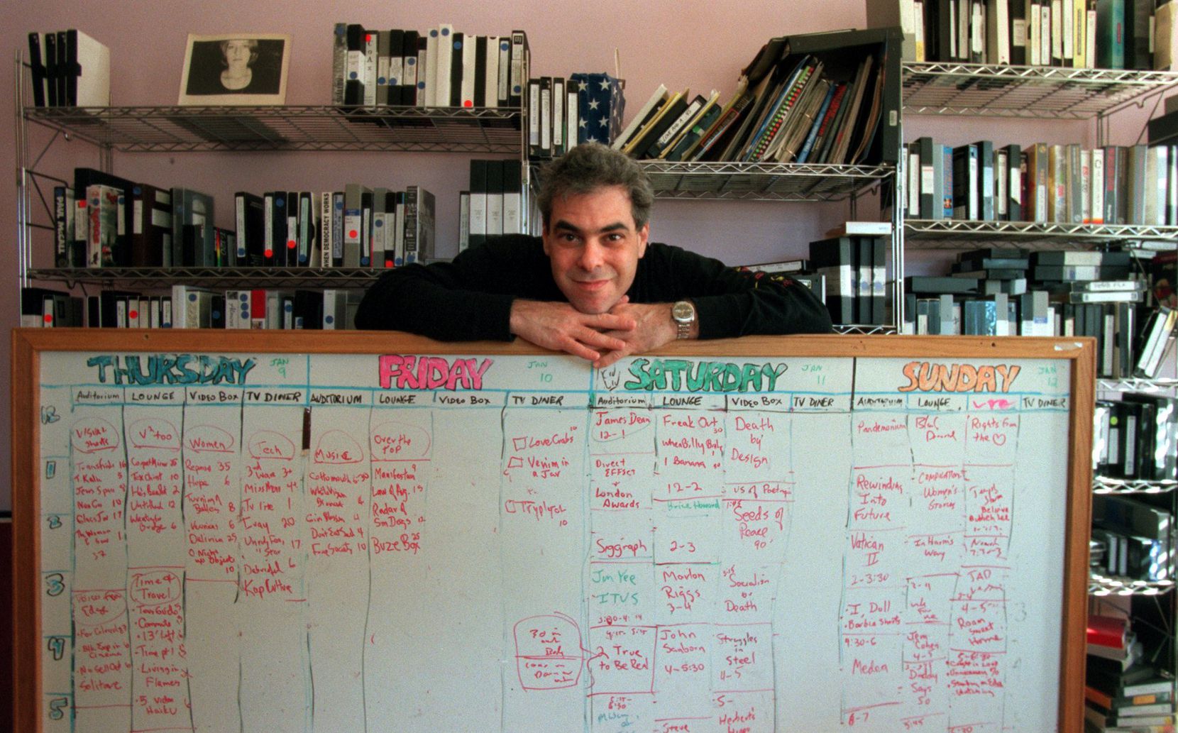 Bart Weiss stands behind the whiteboard he used for years to build the Dallas Video Festival...