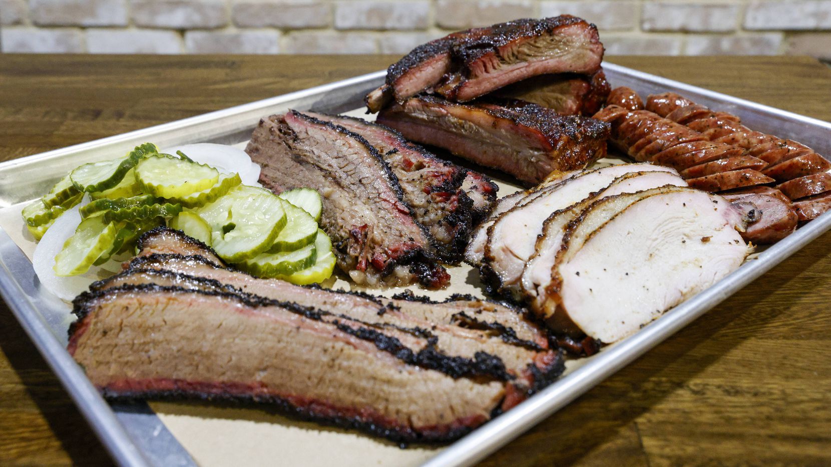 A platter of brisket, Turkey, sausage and beef ribs sits on a table at True Texas BBQ inside...