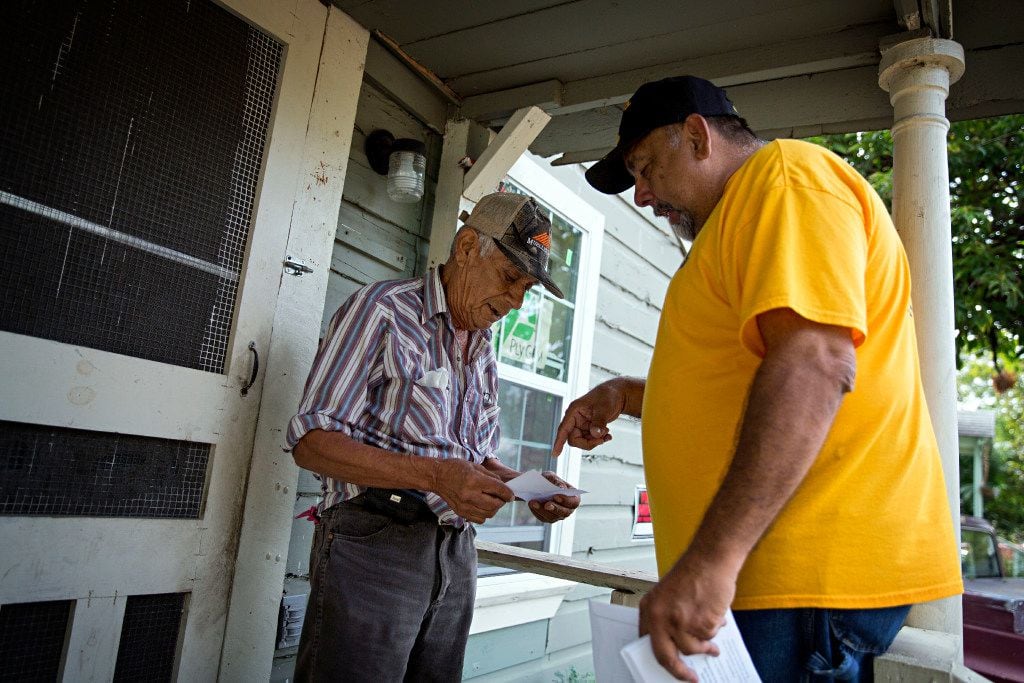 Community organizer Ronnie Mestas hands a flier to resident Fernando Gonzalez on McBroom Street. Many residents in the West Dallas neighborhood are being evicted from their rent homes, which are managed by HMK Limited. (G.J. McCarthy/Staff Photographer)
