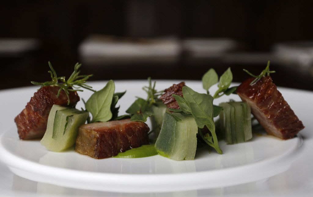 Gyutoro, a 72-hour short rib set on spinach puree, is garnished with slabs of green apple...