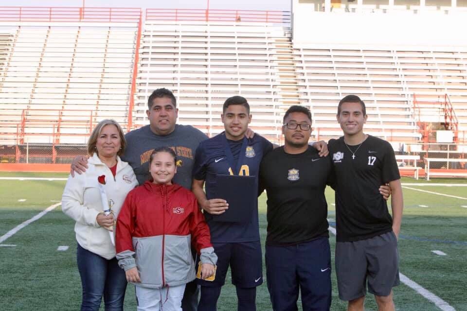 Photo caption: Arlington Lamar junior Jasub Flores poses with his family and coach on senior...