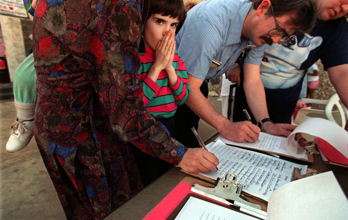 Ashley Hackney, 7, of Arlington waits while her mother, Julia, signs a petition at the site of  Amber Hagerman's abduction. At right: James Sasser, 43, of  Arlington, gets assistance from Bruce Seybert, 39, of Arlington as he signs the petition. Seybert and others spearheaded  an effort for the state to make an Amber Hagerman amendment to the Ashley Astell bill. That amendment would mandate, among  other things, a mandatory life sentence without parole for  convicted child sex offenders. Seybert said an estimated 1,000 people a day visited the site of Amber's abduction.