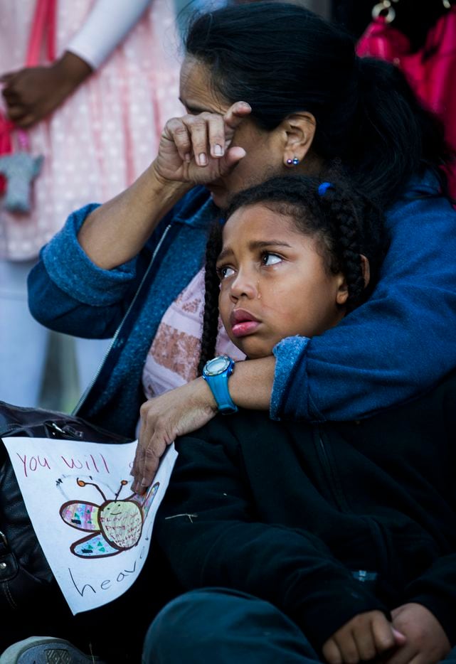 Diana Delgado wipes away a tear as she holds her crying grandson, Lejohn Rogers, 7, during a vigil at a memorial for Sherin Mathews.