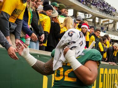 Baylor defensive lineman Siaki Ika covers his face with a towel as he leaves the field after...