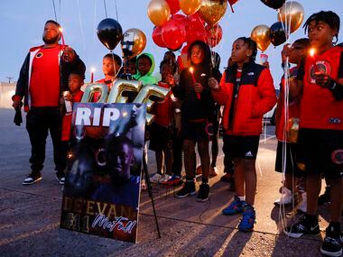 Coach Lo Williams stands with teammates of 11-year-old De’Evan McFall as they pose for...