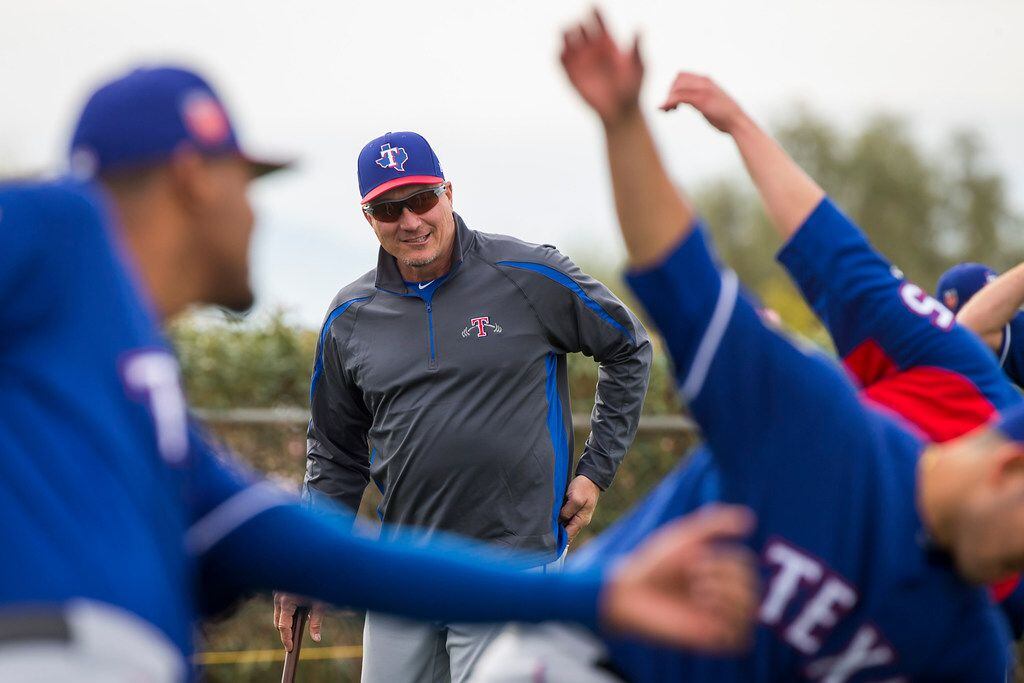Texas Rangers manager Jeff Banister watches as a group or pitchers stretches during a spring...