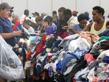 A table filled with used clothing for displaced Houston residents is besieged by those in...