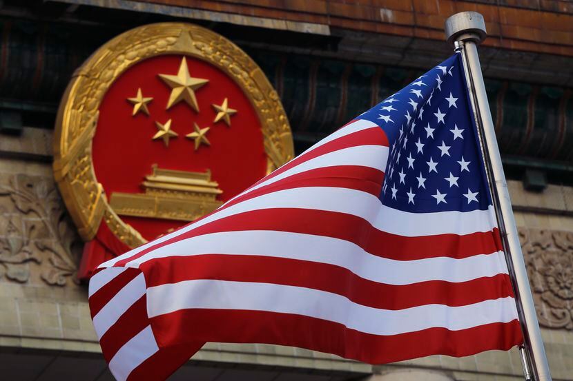 FILE - An American flag is flown next to the Chinese national emblem during a welcome...