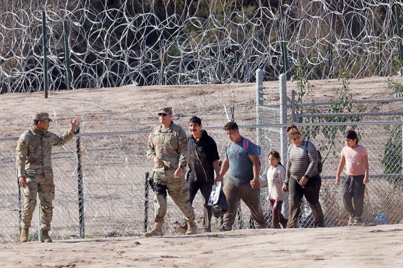 Migrants are escorted by U.S. soldiers with the 508th Military Police Company from New...