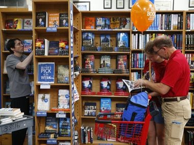 Allen Watson (left) sorts books as Lily Dorris, 13, and her father, Anthony Dorris, browse...