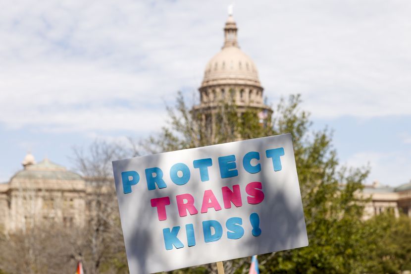 An attendee raises a “Protect Trans Kids” sign in front of the Texas State Capitol during a...
