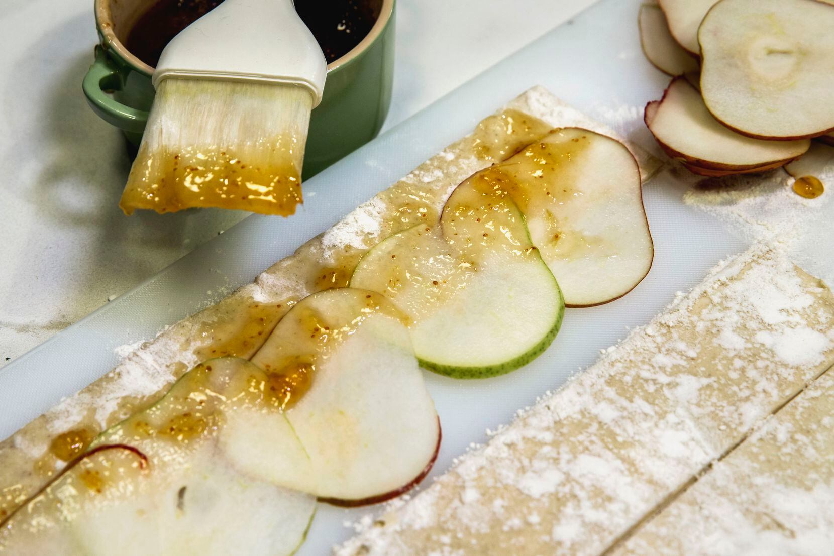 Sliced pears arranged onto 2-inch puff pastry segments topped with fig preserves