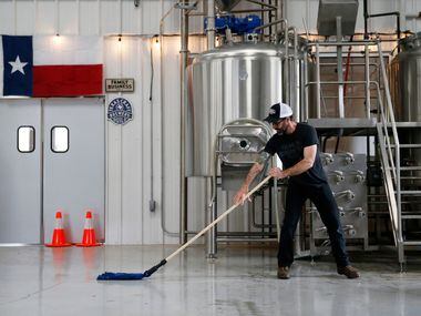 Nate Seale, head brewer mops the floor of the brewhouse at Family Business Beer Company in...