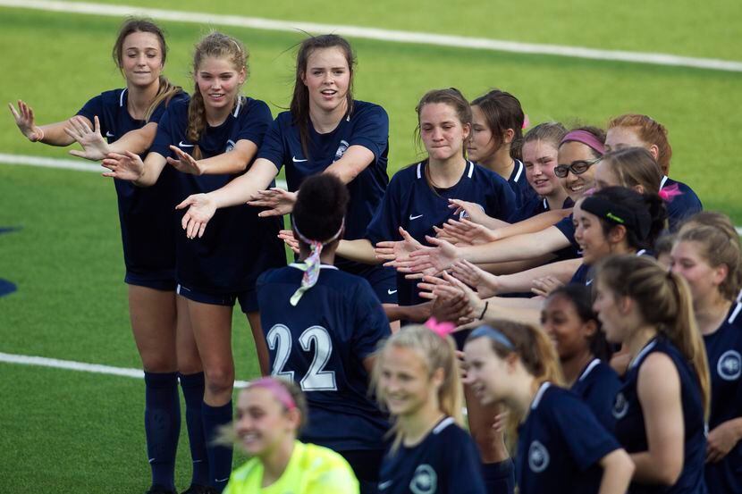 Flower Mound players form a curved reception line to welcome teammate Lexie Ryan (22) to the...