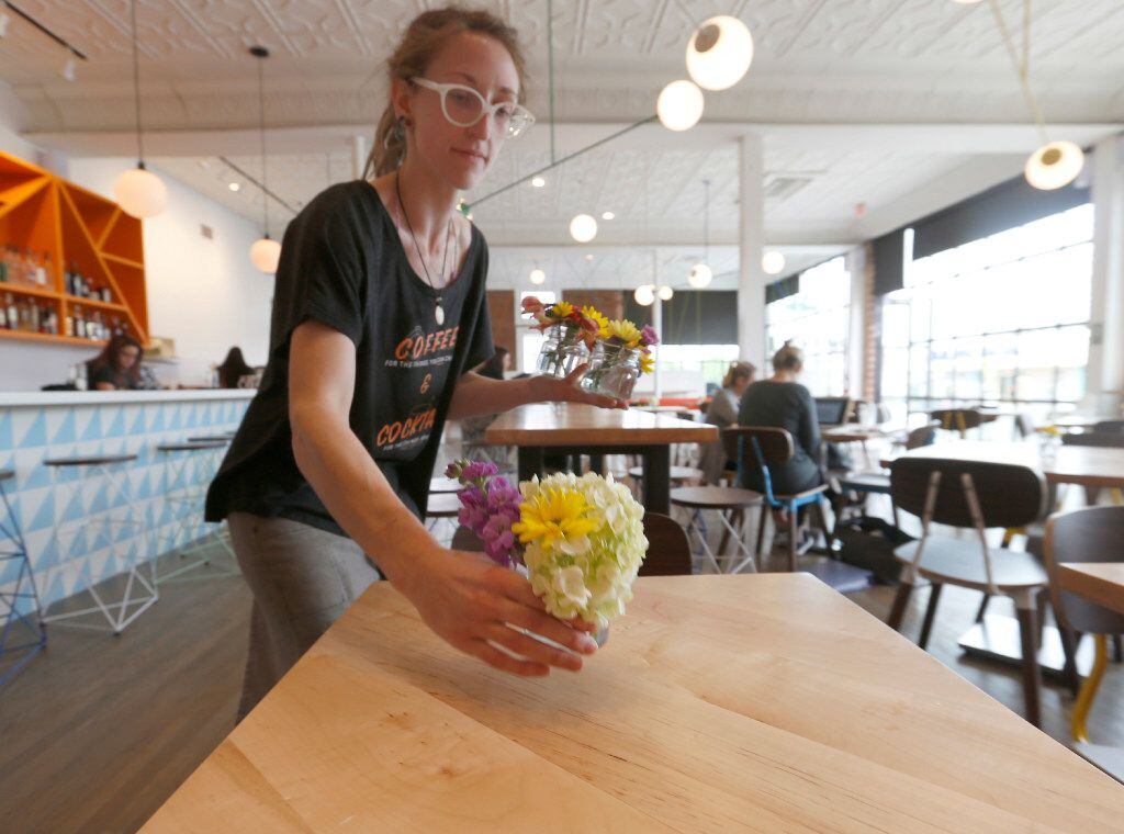 Halcyon Coffee Bar and Lounge staffer Brooke Stalker places fresh flower center pieces in...