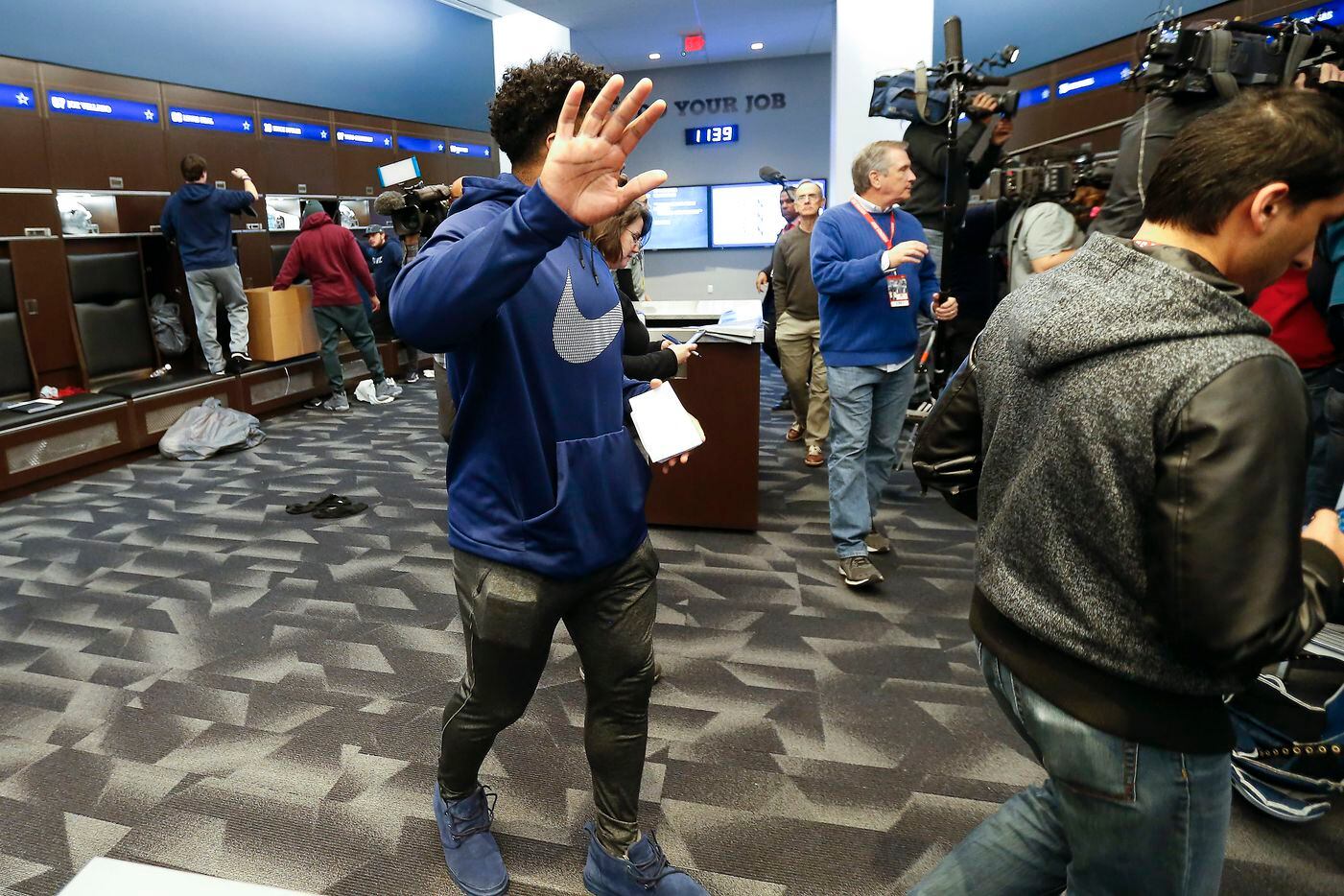Dallas Cowboys running back Ezekiel Elliott shields his face from the camera as he walks in...
